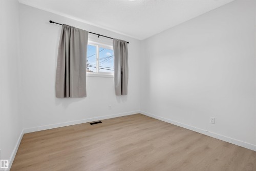 Room featuring light wood-finish flooring, white walls, and a window with a black curtain rod - 7304/7306 78 Avenue, Edmonton, AB 