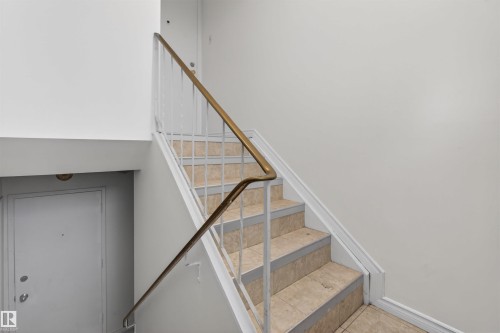 Tile-finished staircase with a metal railing featuring a brass-toned handrail - 7304/7306 78 Avenue, Edmonton, AB 