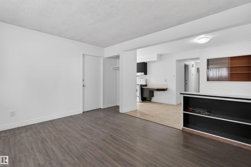 Spacious living area featuring wood-finish flooring, white baseboards, and a neutral color palette - 7304/7306 78 Avenue, Edmonton, AB 