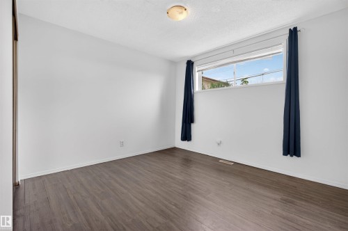 Room featuring wood-finish flooring, white walls, and a large window - 7304/7306 78 Avenue, Edmonton, AB 