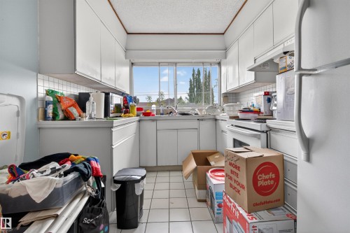 Kitchen featuring white cabinetry, white square tile flooring, white subway tile backsplash, and a large window above the sink - 7304/7306 78 Avenue, Edmonton, AB 