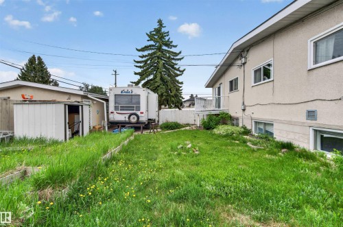 Rear exterior featuring a stucco facade, white trim windows, and an upper-level balcony with white railing - 7304/7306 78 Avenue, Edmonton, AB 