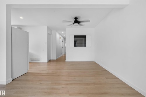 Spacious interior featuring wood-finish flooring, recessed lighting, and a contemporary ceiling fan - 7304/7306 78 Avenue, Edmonton, AB 