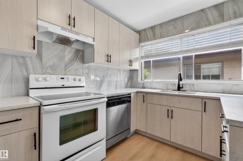 Modern kitchen with light wood-finish cabinetry and matte black hardware - 7304/7306 78 Avenue, Edmonton, AB 