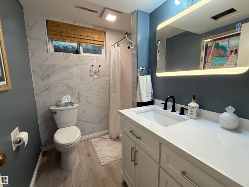 Bathroom with a white vanity featuring an integrated sink and matte black faucet - 10912 50 Street, Edmonton, AB 