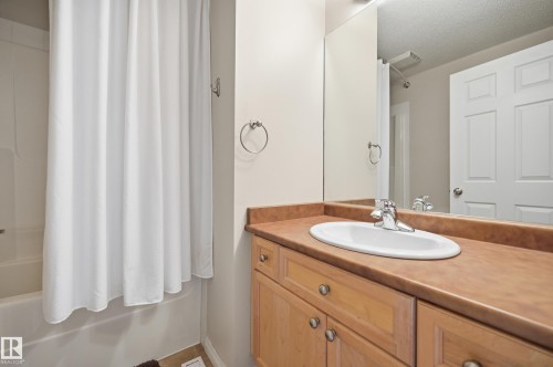 Bathroom featuring a wood-finish vanity with a built-in sink, a large mirror, and a full bathtub with a shower - 11628 167A Avenue, Edmonton, AB - Indoor Photo Showing Bathroom