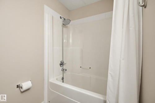 Bathtub and shower combination featuring a chrome fixtures, white subway tile surround, and a coordinating white shower curtain - 11628 167A Avenue, Edmonton, AB - Indoor Photo Showing Bathroom