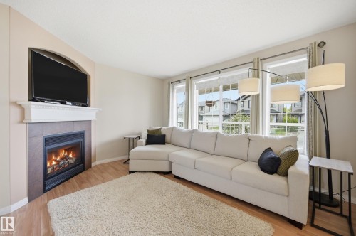Living area featuring light wood-finish flooring and a tiled fireplace with a white mantel - 11628 167A Avenue, Edmonton, AB - Indoor Photo Showing Living Room With Fireplace