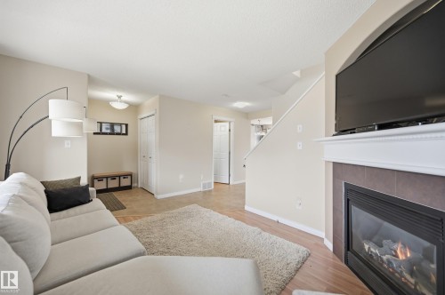 Living area featuring a fireplace with a tiled surround and white mantel, wood-finish flooring, and neutral wall tones - 11628 167A Avenue, Edmonton, AB - Indoor Photo Showing Living Room With Fireplace
