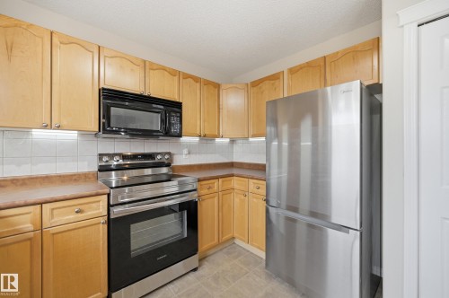 Kitchen featuring natural wood-finish cabinetry, stainless steel appliances, a white tile backsplash, and light-toned countertops - 11628 167A Avenue, Edmonton, AB - Indoor Photo Showing Kitchen With Stainless Steel Kitchen