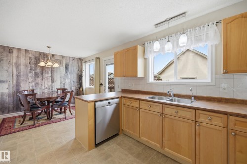 Kitchen and dining area featuring light wood cabinetry and neutral tile flooring - 11628 167A Avenue, Edmonton, AB - Indoor Photo Showing Kitchen With Double Sink