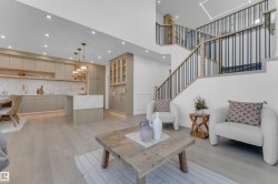 Open-concept living space with light wood-finish flooring, a contemporary kitchen, and a multi-level staircase - 