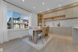 Open-concept dining area featuring light wood-finish flooring, a large multi-pane window, and recessed ceiling lighting - 