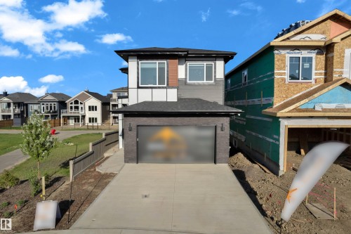 Contemporary two-story residence featuring a striking multi-textured facade with dark brick, gray siding, and white and brown accent panels - 206 Linden Loop, Leduc, AB 