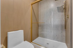 Shower enclosure with gold-toned framing, full glass panel, rainfall shower head, and handheld shower wand - 