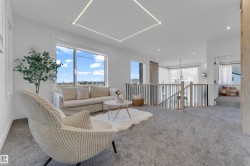 Bright open loft area with plush gray carpeting and a contemporary railing system featuring dark and light wood-tone spindles - 