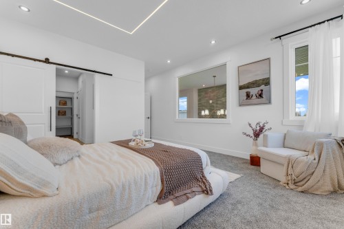 Carpeted room featuring recessed lighting, a sliding barn door, an interior window, and two exterior windows - 206 Linden Loop, Leduc, AB 