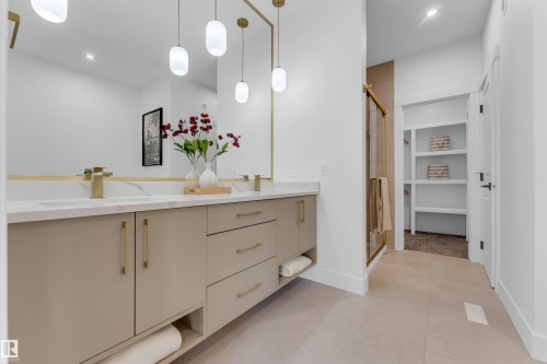 Dual vanity with white countertops and undermount sinks, complemented by gold-finish faucets and hardware - 206 Linden Loop, Leduc, AB 