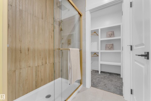 Walk-in shower featuring a gold-finish frame and wood-look tile surround - 206 Linden Loop, Leduc, AB 