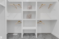 Custom built-in closet system featuring white shelving, multiple hanging rods, and an integrated central shelving unit - 