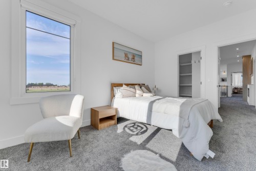 Large window with white trim, gray carpeted flooring, built-in closet shelving, bright white walls, and a recessed doorway - 206 Linden Loop, Leduc, AB 