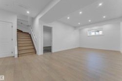 Spacious lower-level room featuring light wood-finish flooring and recessed lighting - 