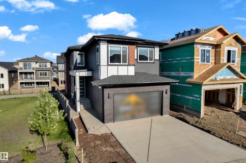Contemporary exterior with dark siding accents, a two-car garage, and a concrete driveway - 206 Linden Loop, Leduc, AB 
