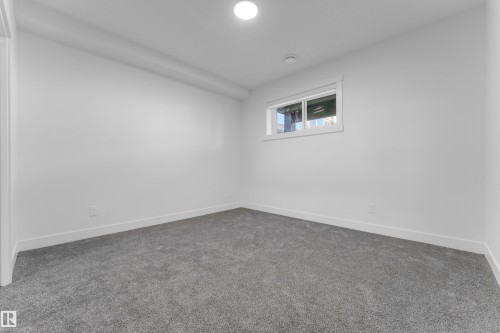 Carpeted room featuring a single window, white walls, white baseboards, and a circular ceiling light fixture - 206 Linden Loop, Leduc, AB 
