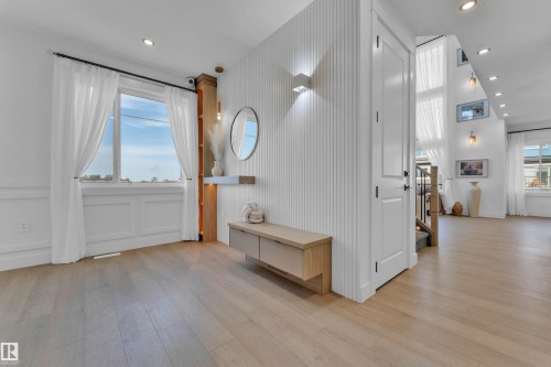 Entryway featuring wood-finish flooring, a built-in floating cabinet, a wall-mounted mirror, and decorative wall paneling - 206 Linden Loop, Leduc, AB 