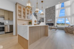 Open-concept living area featuring a kitchen island with a quartz countertop and wood-slat base, wood-finish flooring, and a stone-accented fireplace - 