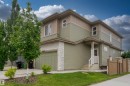 Contemporary exterior featuring two-tone siding, a stone veneer garage surround, and a covered entry - 2104 160 Street Sw, Edmonton, AB 