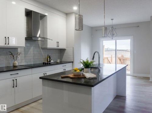 Modern kitchen featuring an expansive center island with an integrated sink and gooseneck faucet - 2104 160 Street Sw, Edmonton, AB 