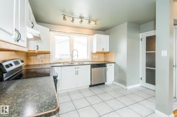 Kitchen featuring white cabinetry, tile backsplash, stainless steel dishwasher, track lighting, and a window above the sink - 