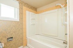 Bathroom featuring a white bathtub, integrated shower surround, and a wall-mounted showerhead with a handheld sprayer - 