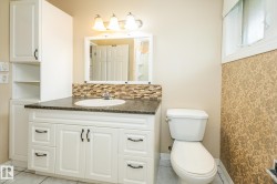 Bathroom featuring white vanity with granite-look countertop, integrated sink, and mosaic tile backsplash - 