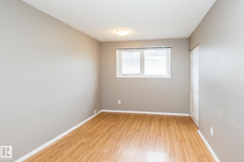Room featuring wood-finish flooring, a white trim baseboard, and light gray walls - 7543 149A Avenue, Edmonton, AB 