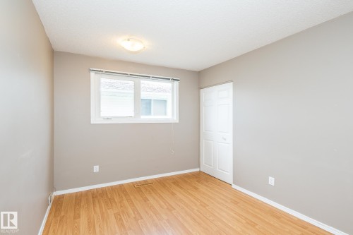 Room featuring wood-finish flooring, neutral wall tones, and white baseboards - 7543 149A Avenue, Edmonton, AB 