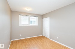 Room featuring wood-finish flooring, neutral wall tones, and white baseboards - 
