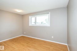 Room featuring wood-finish flooring, neutral gray wall tones, and a single window with white trim - 