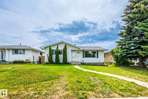 White siding exterior with a contrasting dark roof, featuring a concrete pathway and mature landscaping - 7543 149A Avenue, Edmonton, AB 