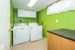 Dedicated laundry area featuring a washer and dryer, overhead cabinetry, and a work surface with a dark countertop - 