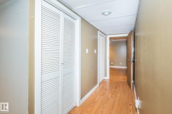Hallway featuring wood-finish flooring, two sets of louvered bifold closet doors, neutral wall paint, and a recessed ceiling light - 