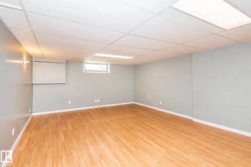 Spacious room featuring wood-finish flooring, light gray walls, and a white drop ceiling with integrated lighting - 7543 149A Avenue, Edmonton, AB 