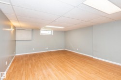Spacious room featuring wood-finish flooring, light gray walls, and a white drop ceiling with integrated lighting - 
