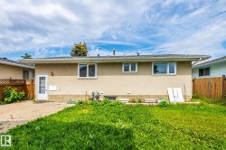 Rear exterior featuring stucco siding, a shingle roof, and multiple windows - 
