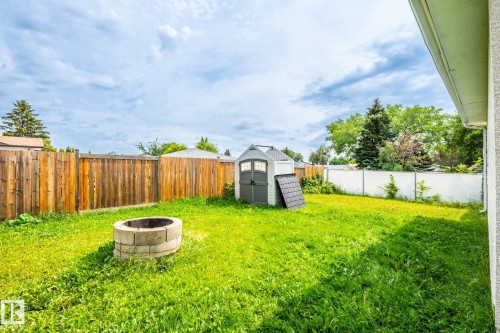 Spacious backyard featuring a block fire pit, a storage shed, and perimeter fencing - 7543 149A Avenue, Edmonton, AB 
