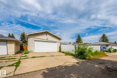 Detached garage with a white panel door, concrete driveway, stucco exterior, and gable roofline - 7543 149A Avenue, Edmonton, AB 