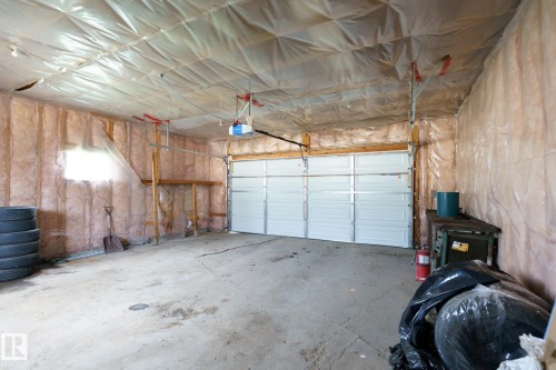 Spacious garage featuring a concrete floor, a white paneled garage door, and a built-in shelf - 7543 149A Avenue, Edmonton, AB 