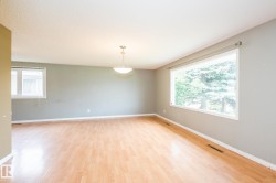 Spacious room featuring wood-finish flooring, light grey walls, and a large picture window - 