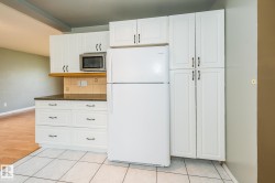 Kitchen featuring white cabinetry, dark countertops, a tile backsplash, and a built-in microwave - 